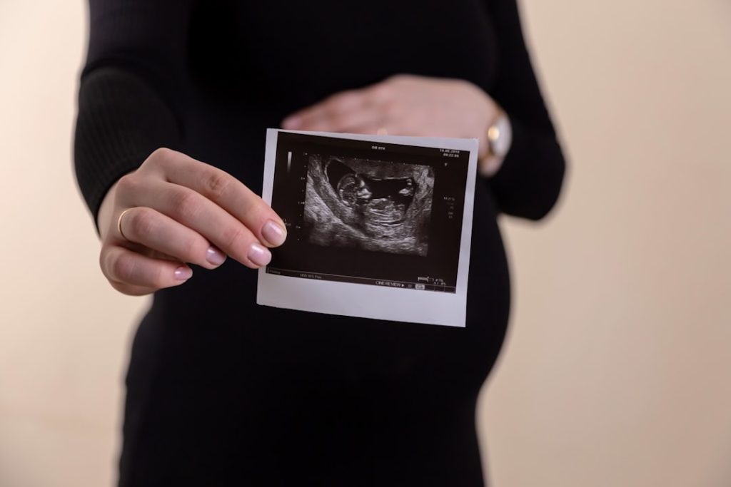 a-person-holding-a-tablet-87ev1nvhdsu Cropped image of young pregnant woman holding ultrasound picture on belly.
