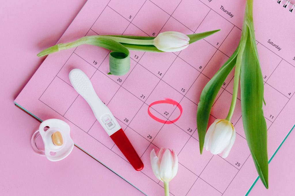 white-and-pink-tulips-on-pink-surface-5982466 Pregnancy test on pink calendar with tulips, symbolizing fertility and new beginnings.